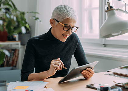 Woman at a desk looking at a tablet