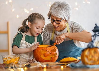 Grandmother and granddaughter carve a pumpkin